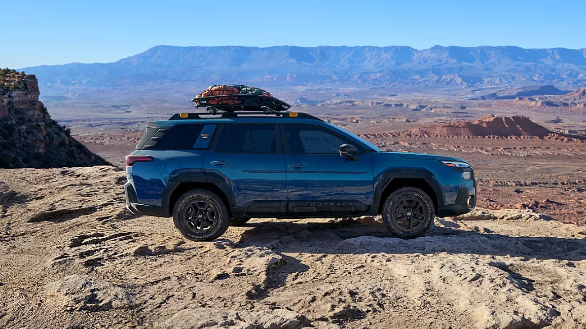 Blue Subaru Outback with a roof basket parked on a rocky desert plateau